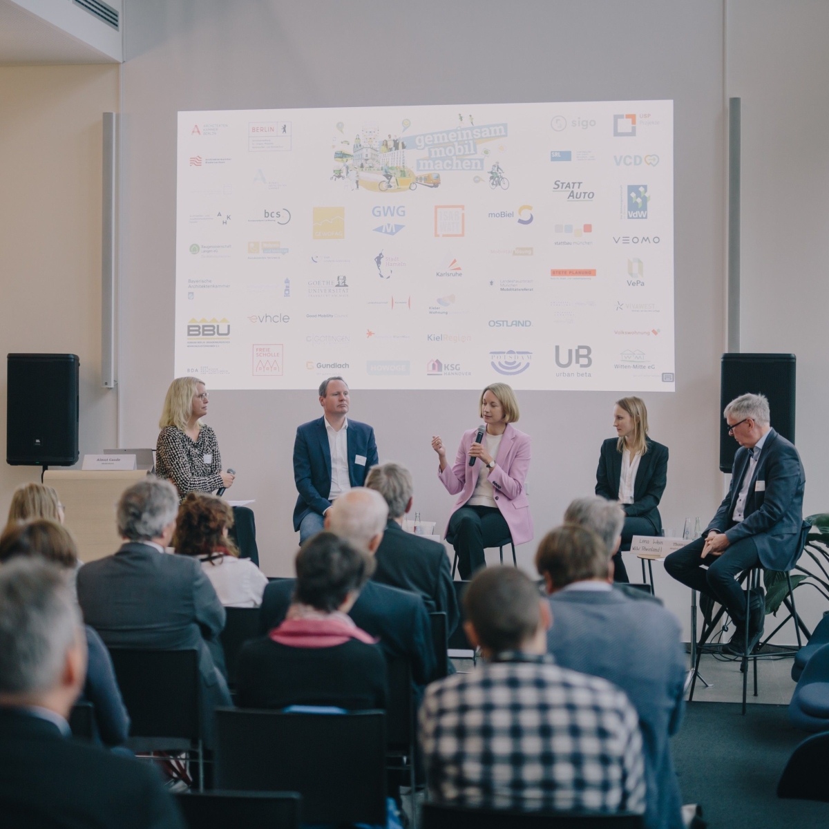 Menschen sitzen auf einem Podium vor Publikum